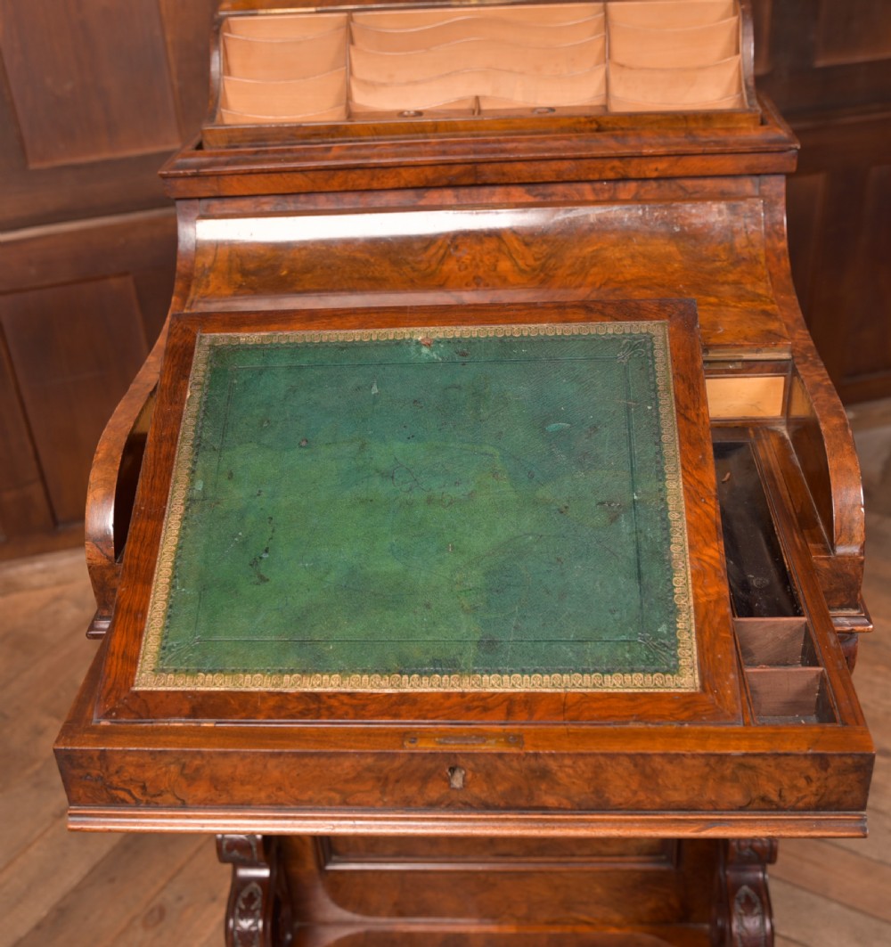 A Victorian burr walnut piano top davenport desk featuring a rounded sloping lid, carved scroll supports, and side drawers with turned wooden knobs. View VII