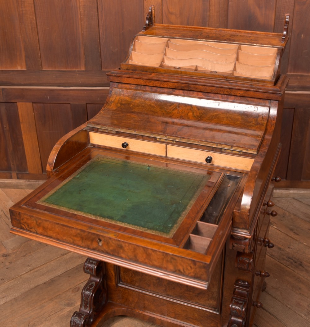 A Victorian burr walnut piano top davenport desk featuring a rounded sloping lid, carved scroll supports, and side drawers with turned wooden knobs. View VIII