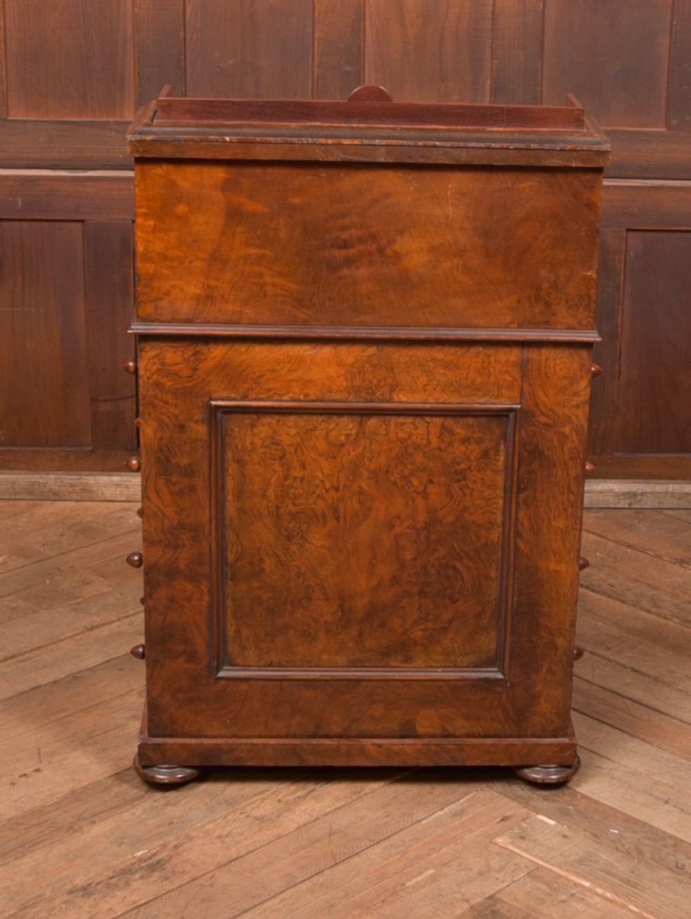 A Victorian burr walnut piano top davenport desk featuring a rounded sloping lid, carved scroll supports, and side drawers with turned wooden knobs. View XI