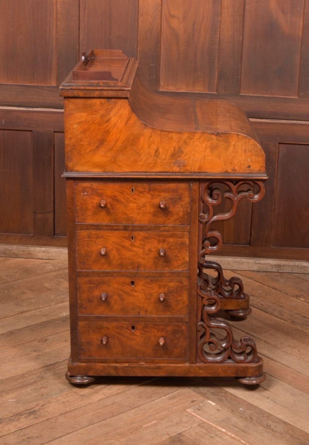 A Victorian burr walnut piano top davenport desk featuring a rounded sloping lid, carved scroll supports, and side drawers with turned wooden knobs. View XII