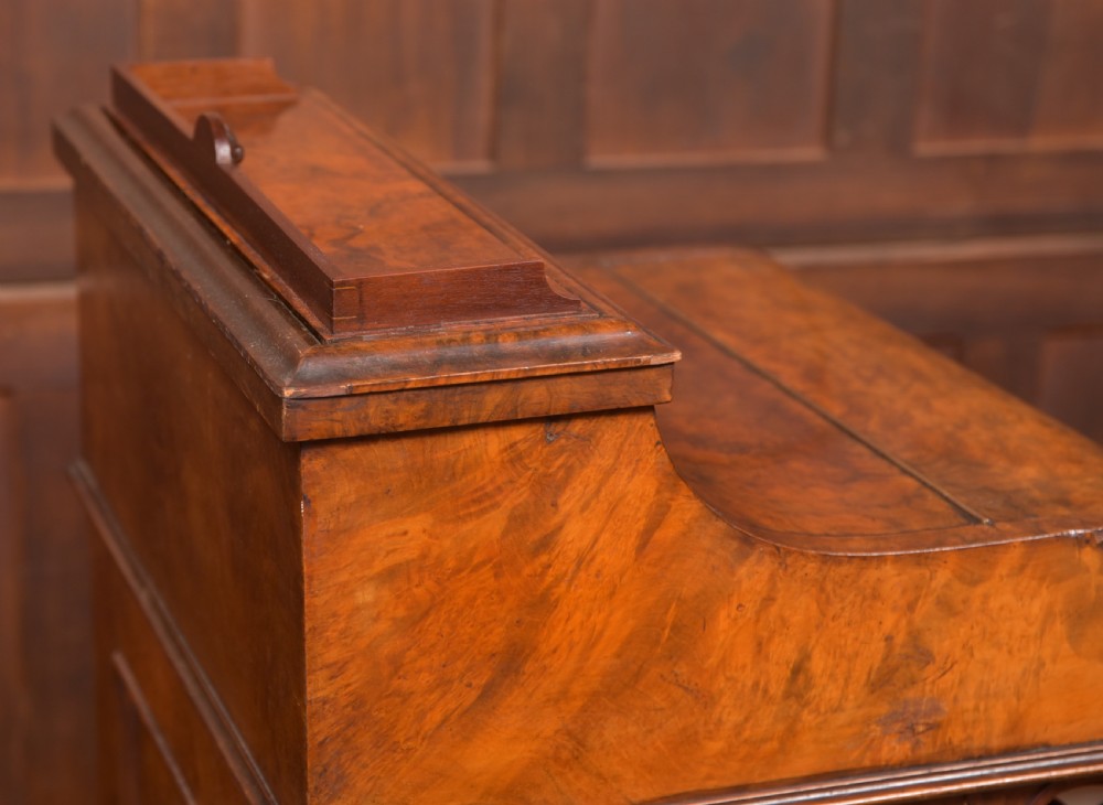 A Victorian burr walnut piano top davenport desk featuring a rounded sloping lid, carved scroll supports, and side drawers with turned wooden knobs. View XIII