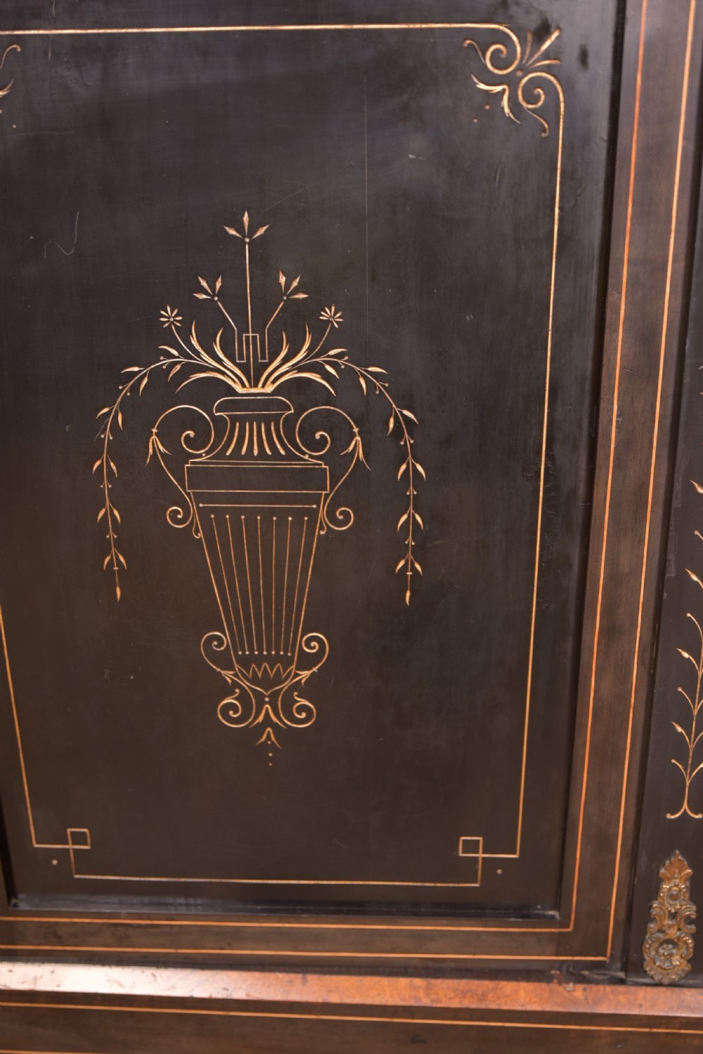A Victorian ebonised breakfront credenza featuring glazed side doors, gilt incised urn motifs, and cast decorative mounts. View VI