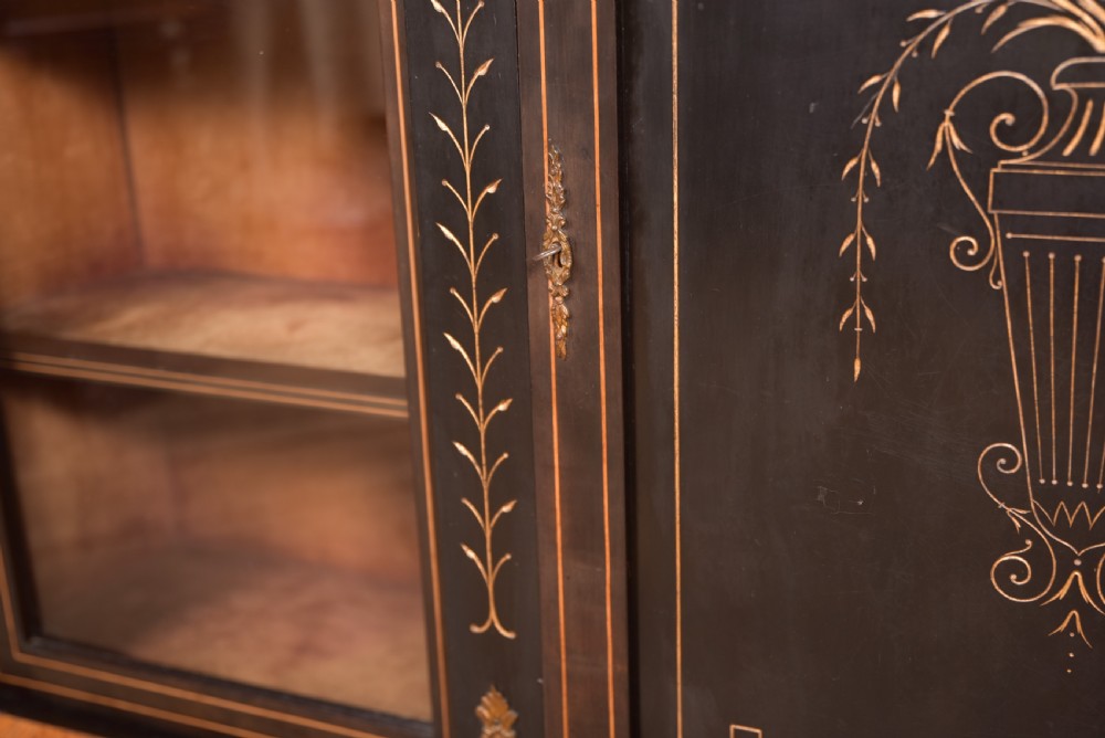 A Victorian ebonised breakfront credenza featuring glazed side doors, gilt incised urn motifs, and cast decorative mounts. View VIII