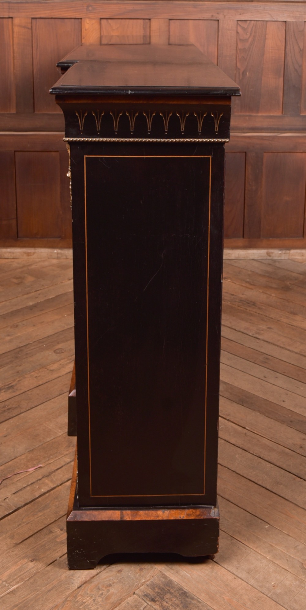 A Victorian ebonised breakfront credenza featuring glazed side doors, gilt incised urn motifs, and cast decorative mounts. View XI