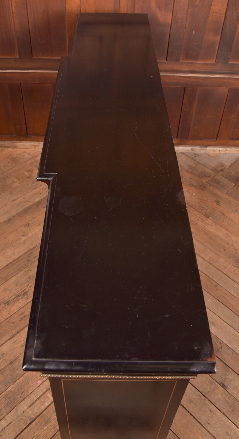A Victorian ebonised breakfront credenza featuring glazed side doors, gilt incised urn motifs, and cast decorative mounts. View XIII