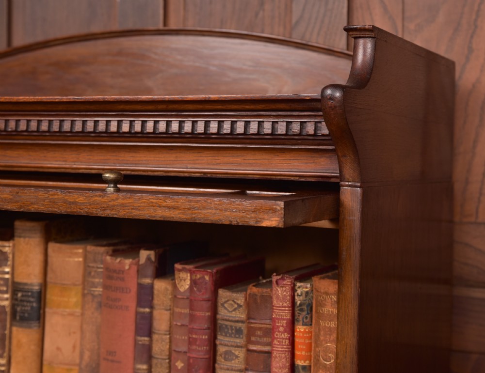 A four-tier dark oak sectional bookcase featuring glass front doors, brass hardware, and a decorative gallery top. View X