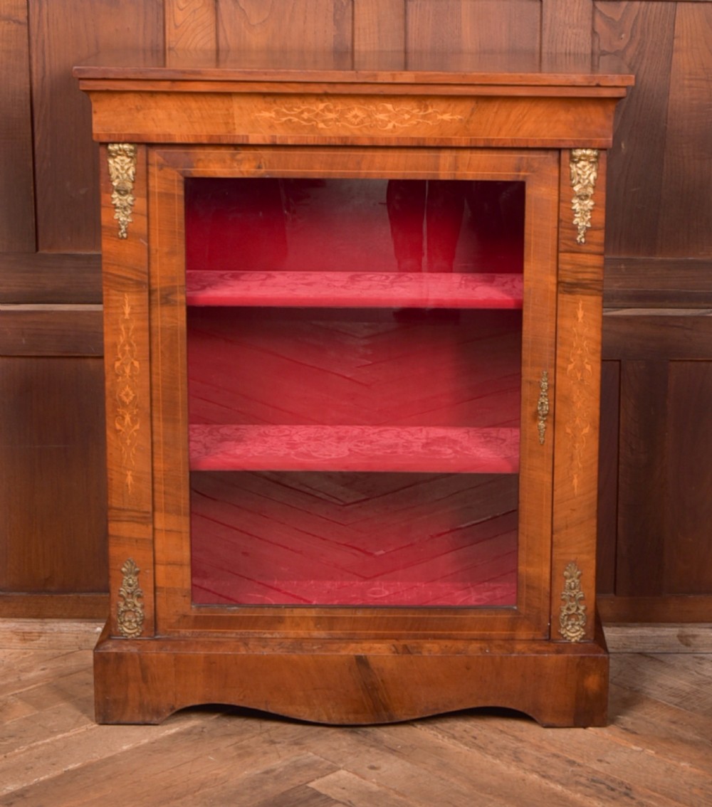A Victorian walnut pier cabinet with a glazed single door, floral marquetry inlay, gilded ormolu mounts, and a red fabric-lined interior with shelves. View II