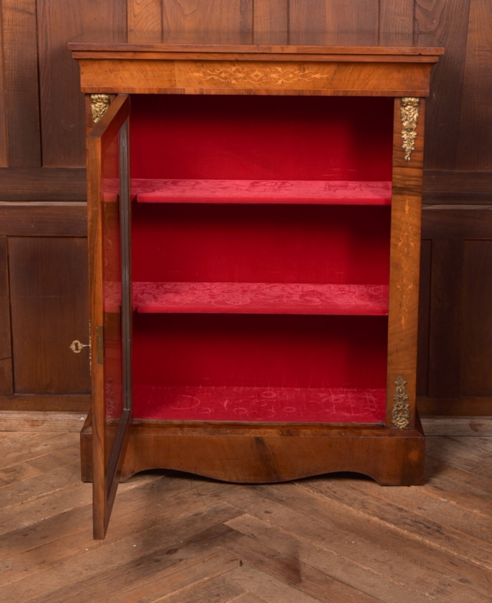 A Victorian walnut pier cabinet with a glazed single door, floral marquetry inlay, gilded ormolu mounts, and a red fabric-lined interior with shelves. View III