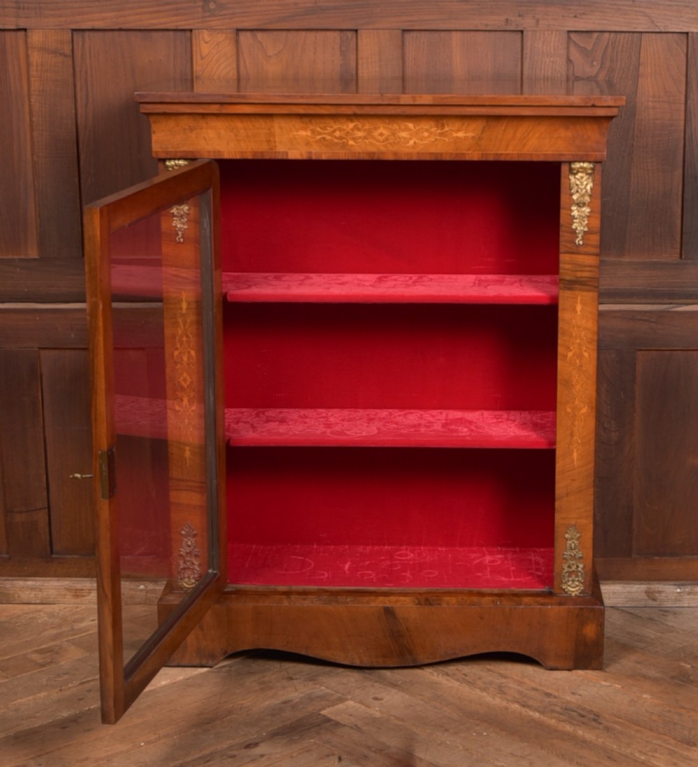 A Victorian walnut pier cabinet with a glazed single door, floral marquetry inlay, gilded ormolu mounts, and a red fabric-lined interior with shelves. View V