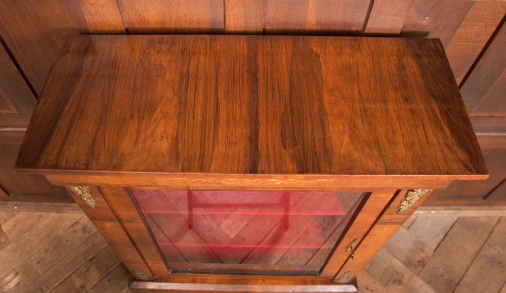 A Victorian walnut pier cabinet with a glazed single door, floral marquetry inlay, gilded ormolu mounts, and a red fabric-lined interior with shelves. View XIV
