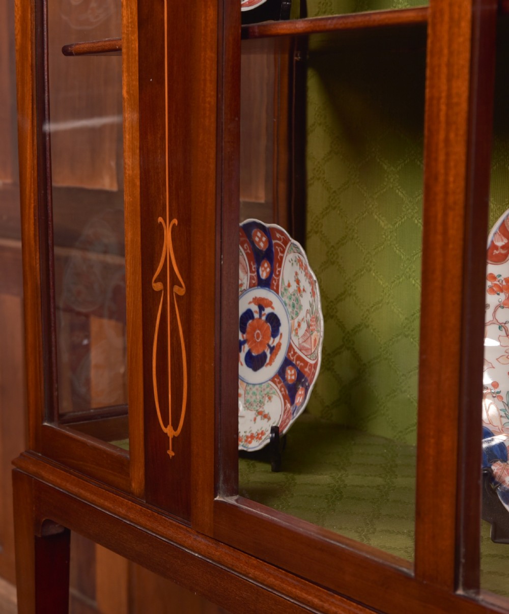 An Art Nouveau mahogany display cabinet featuring stylised floral marquetry inlays, glazed doors, an open upper gallery, and a lower shelf. View III