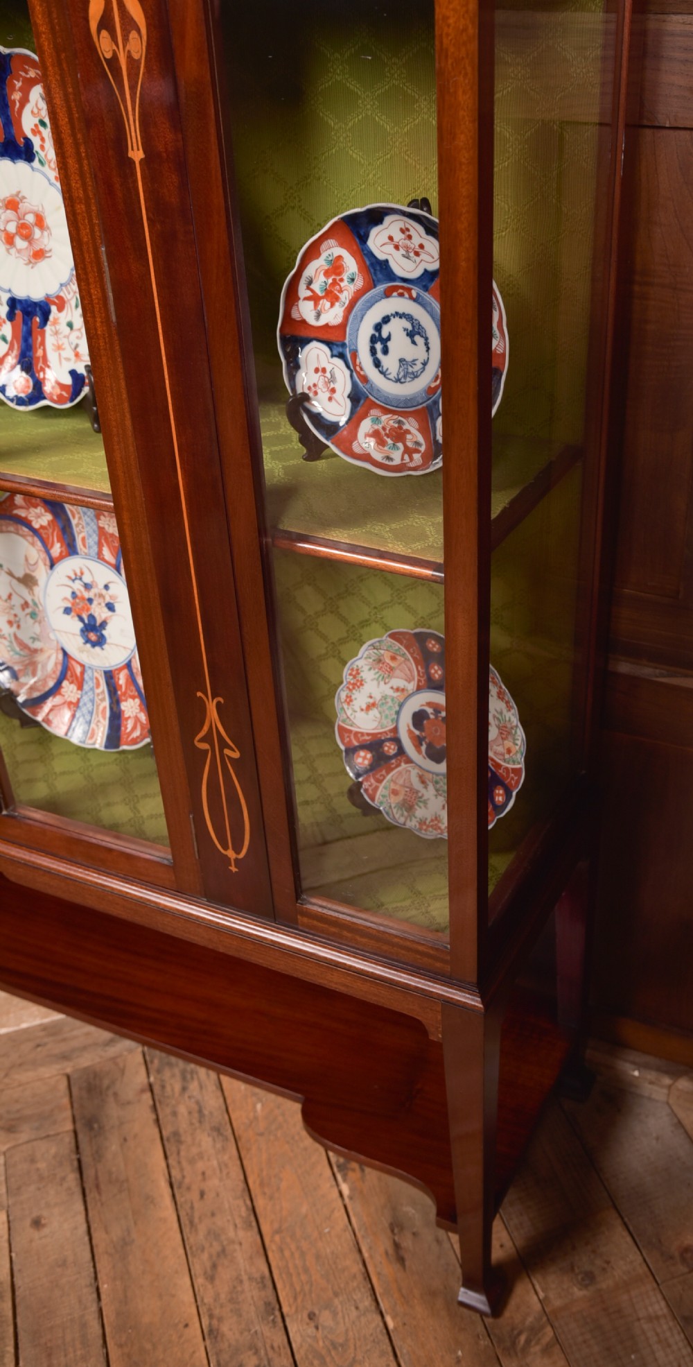 An Art Nouveau mahogany display cabinet featuring stylised floral marquetry inlays, glazed doors, an open upper gallery, and a lower shelf. View V