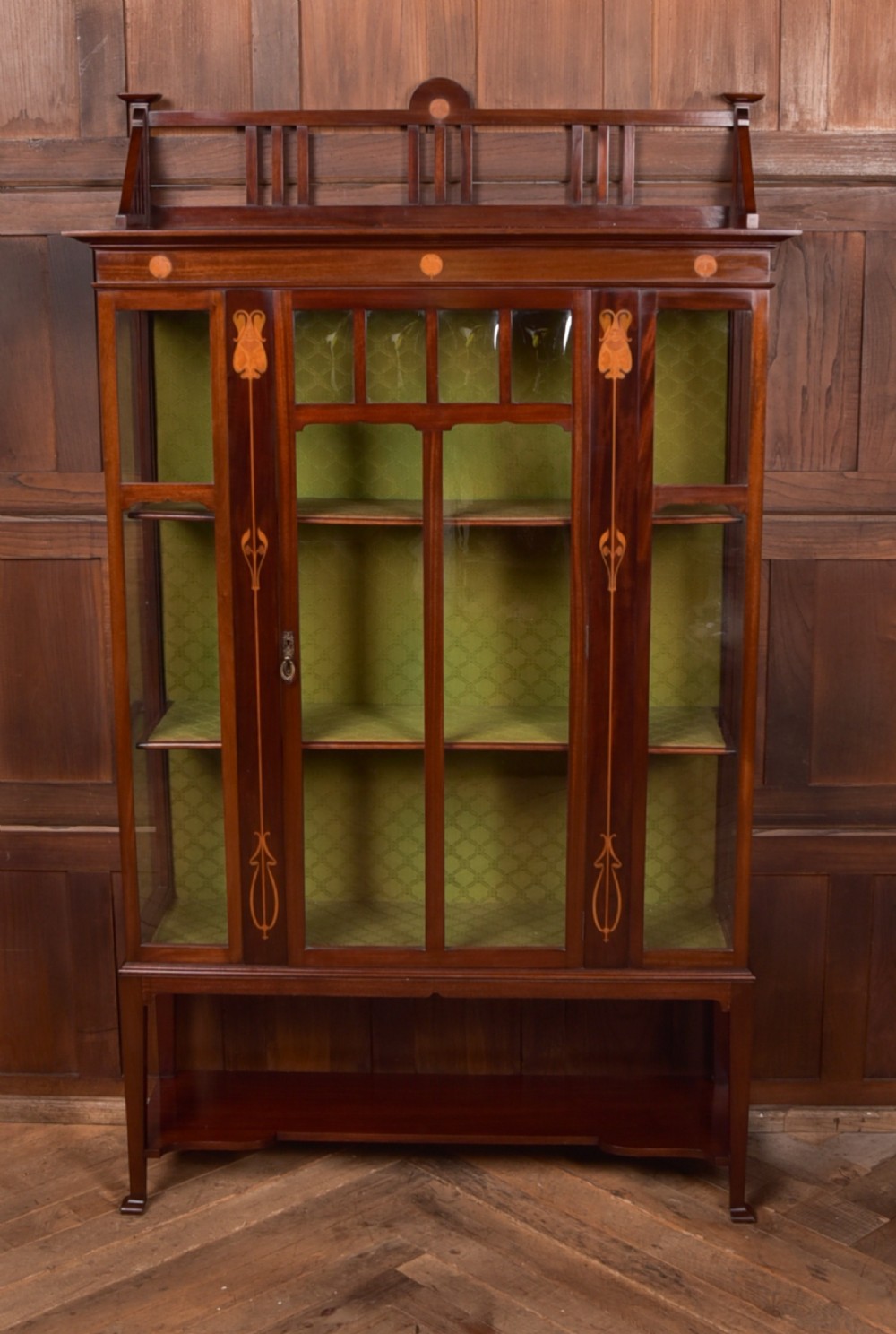 An Art Nouveau mahogany display cabinet featuring stylised floral marquetry inlays, glazed doors, an open upper gallery, and a lower shelf. View IX