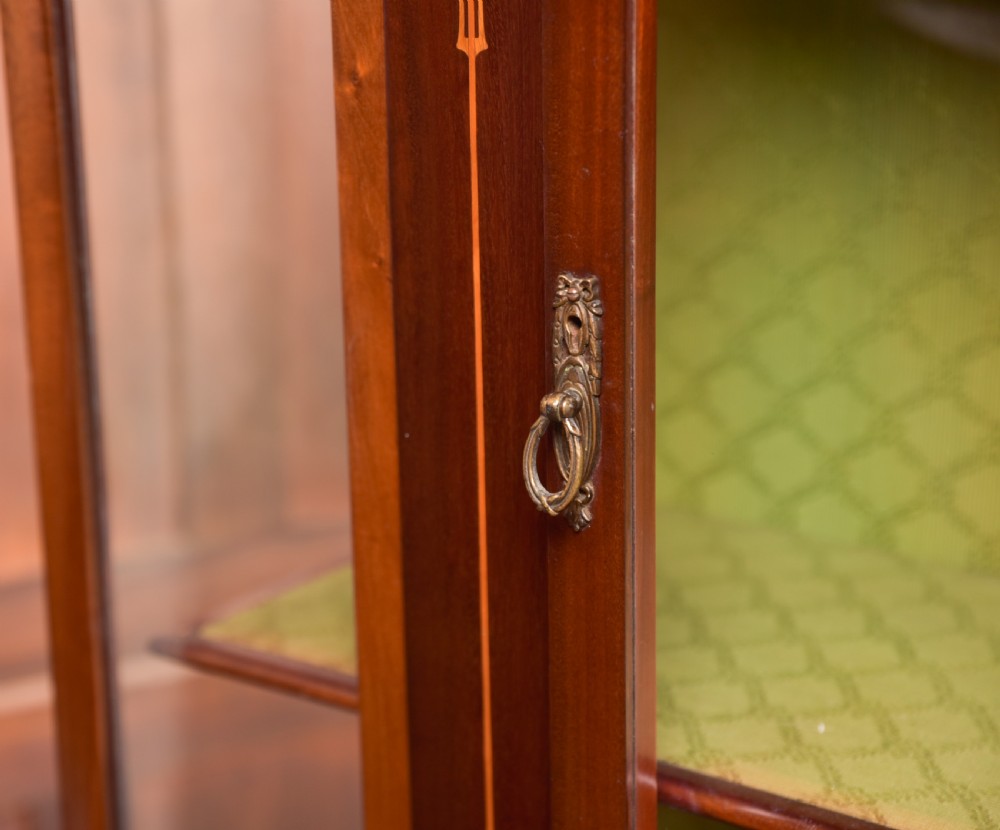 An Art Nouveau mahogany display cabinet featuring stylised floral marquetry inlays, glazed doors, an open upper gallery, and a lower shelf. View XVI