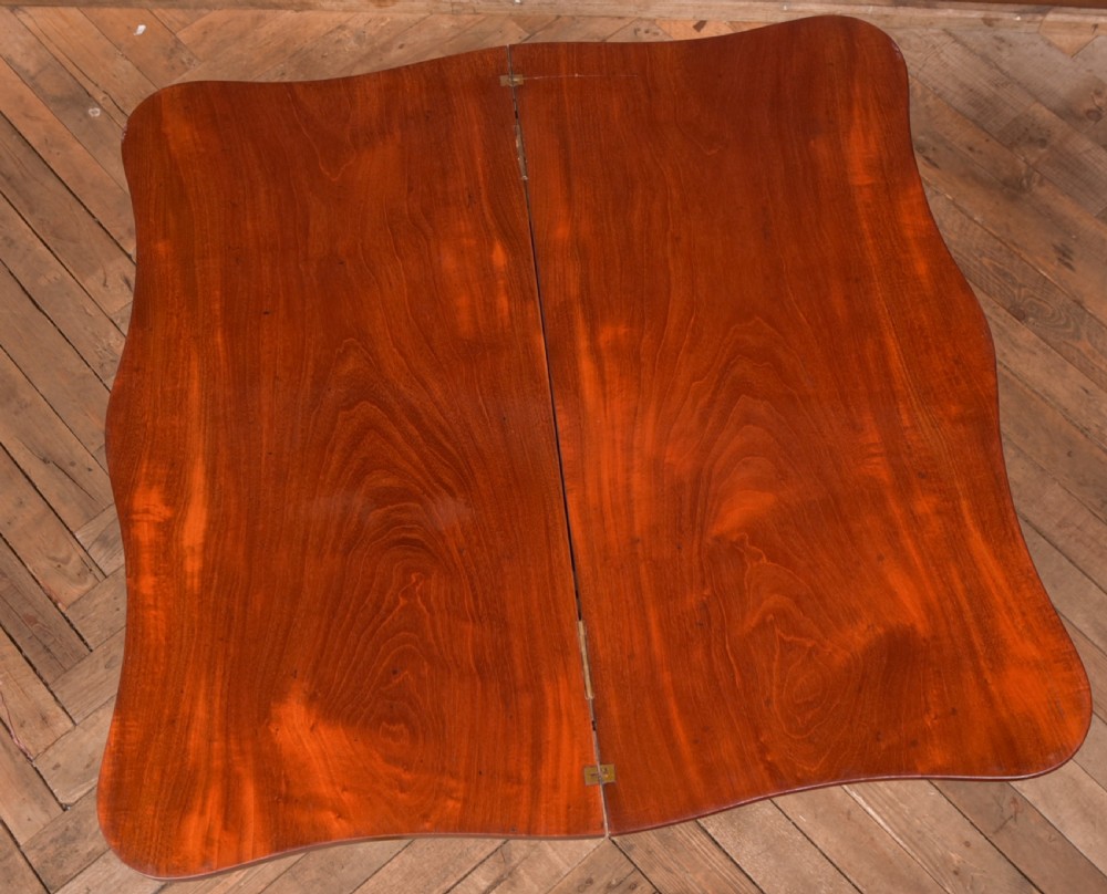 A Victorian mahogany fold-over tea table featuring a serpentine top, bead moulding along the apron, a turned central column, and carved quadruped scroll legs. View XIII