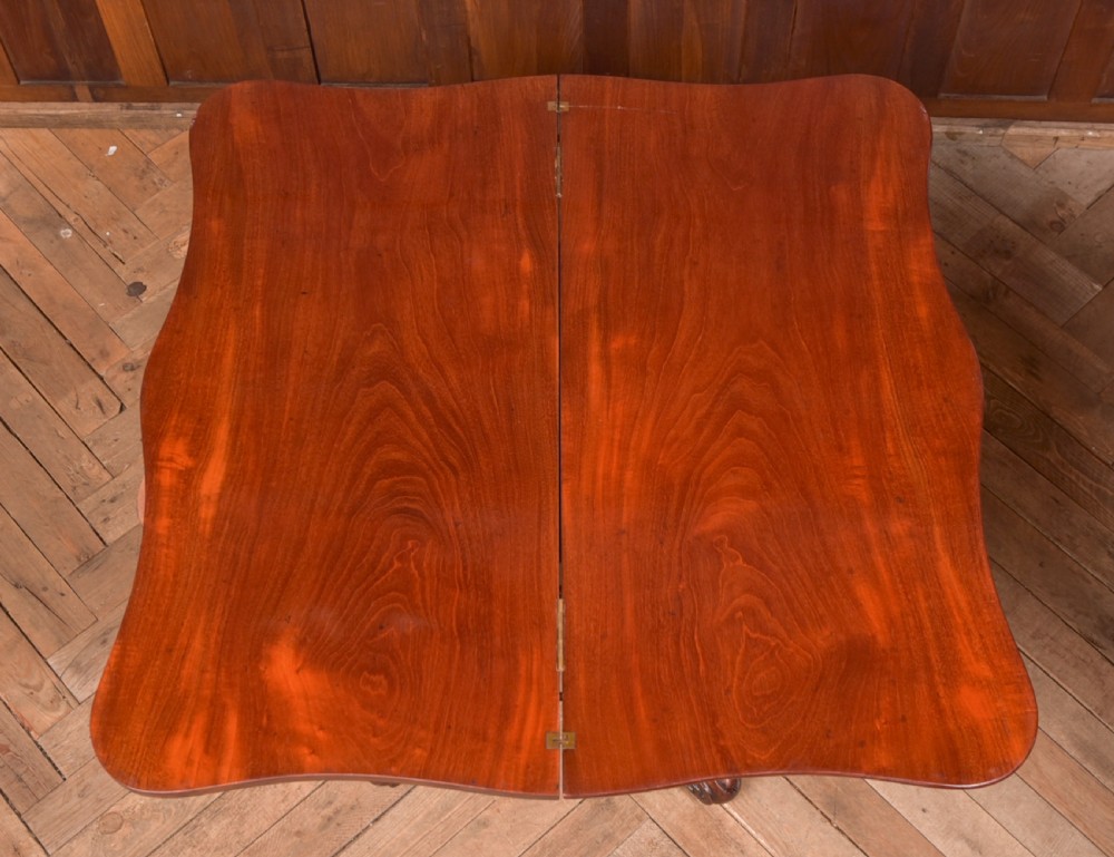A Victorian mahogany fold-over tea table featuring a serpentine top, bead moulding along the apron, a turned central column, and carved quadruped scroll legs. View XIV