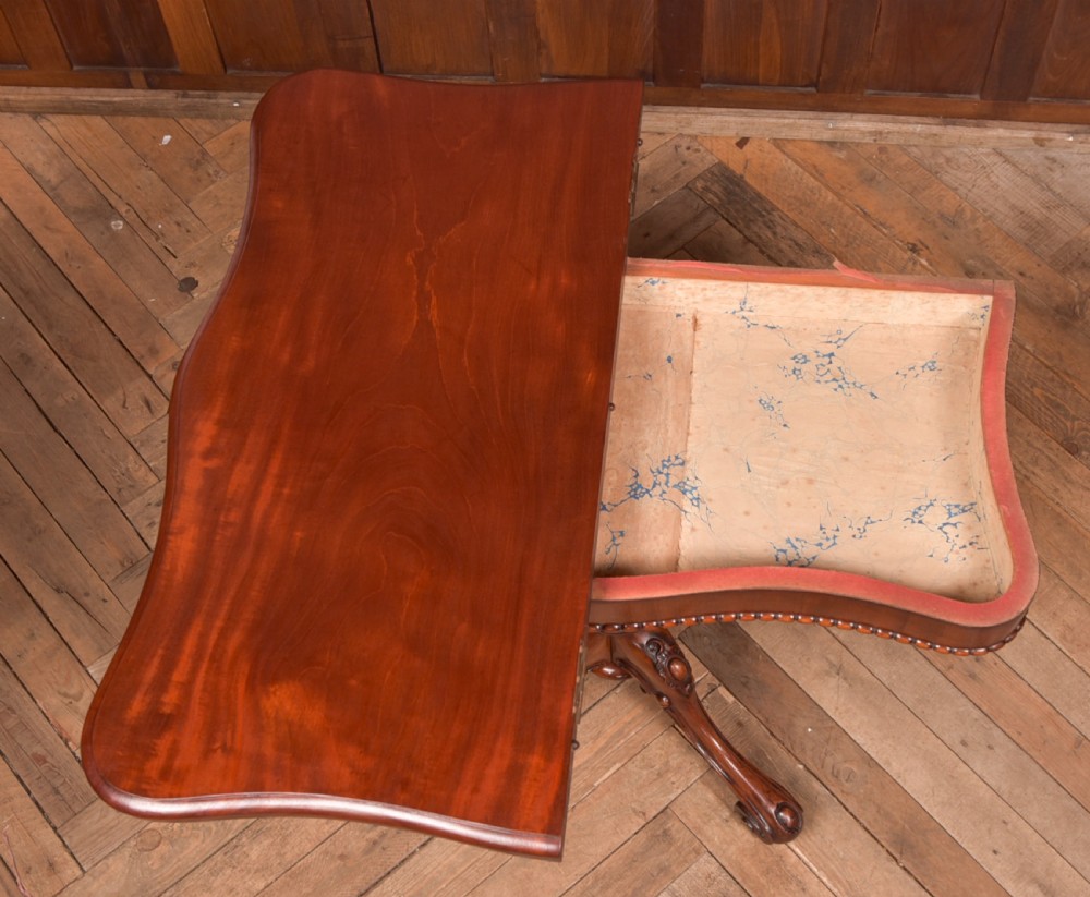 A Victorian mahogany fold-over tea table featuring a serpentine top, bead moulding along the apron, a turned central column, and carved quadruped scroll legs. View XV