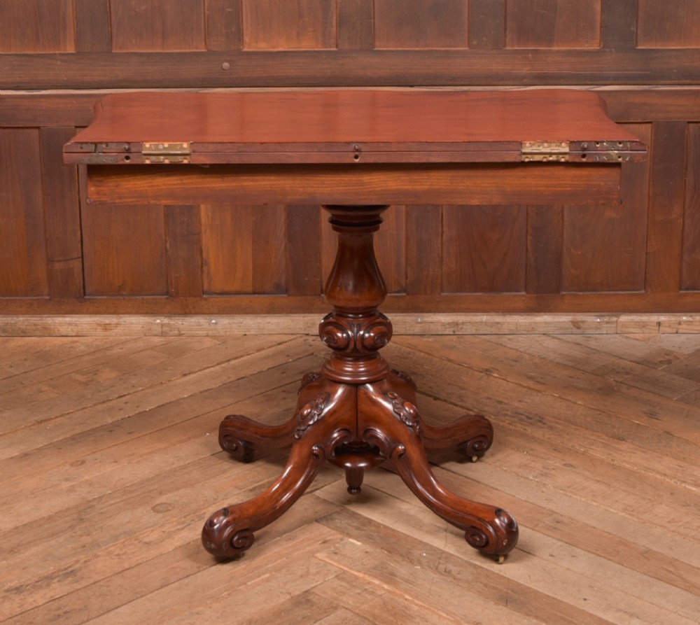 A Victorian mahogany fold-over tea table featuring a serpentine top, bead moulding along the apron, a turned central column, and carved quadruped scroll legs. View XX
