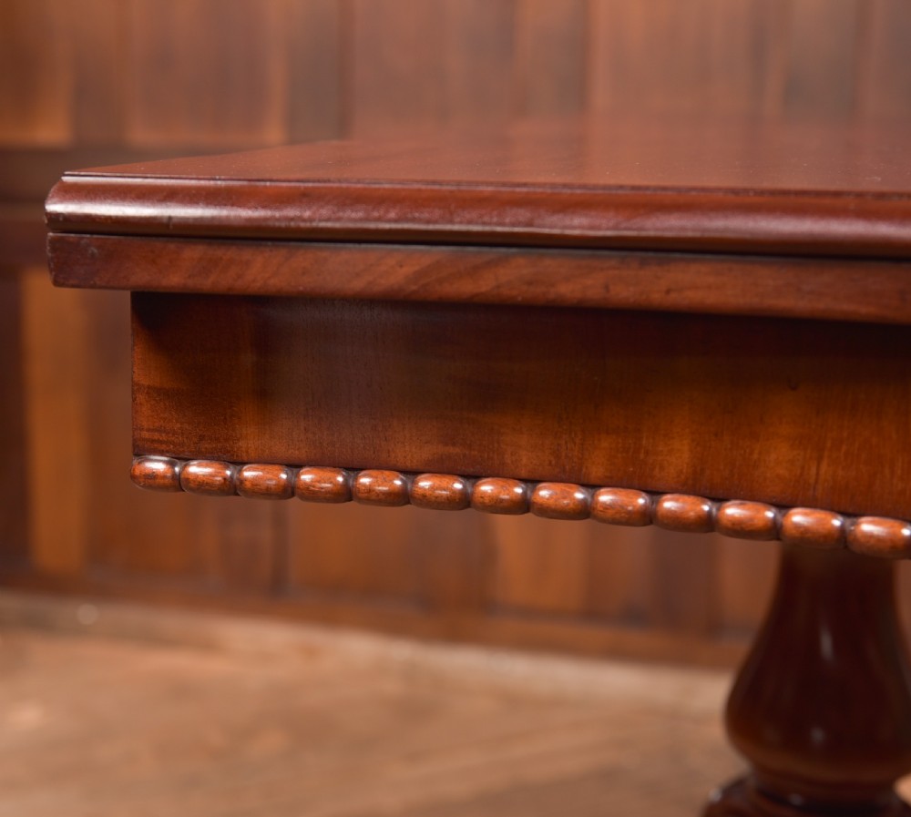 A Victorian mahogany fold-over tea table featuring a serpentine top, bead moulding along the apron, a turned central column, and carved quadruped scroll legs. View XXI