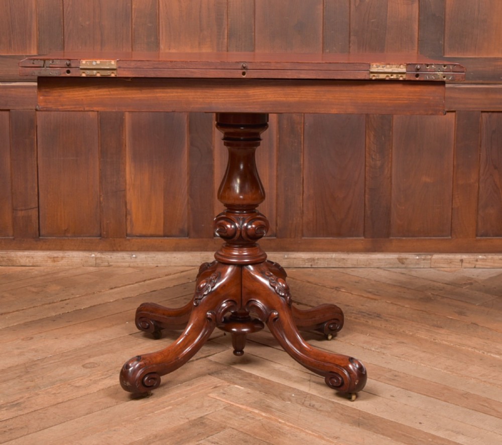 A Victorian mahogany fold-over tea table featuring a serpentine top, bead moulding along the apron, a turned central column, and carved quadruped scroll legs. View XXIII