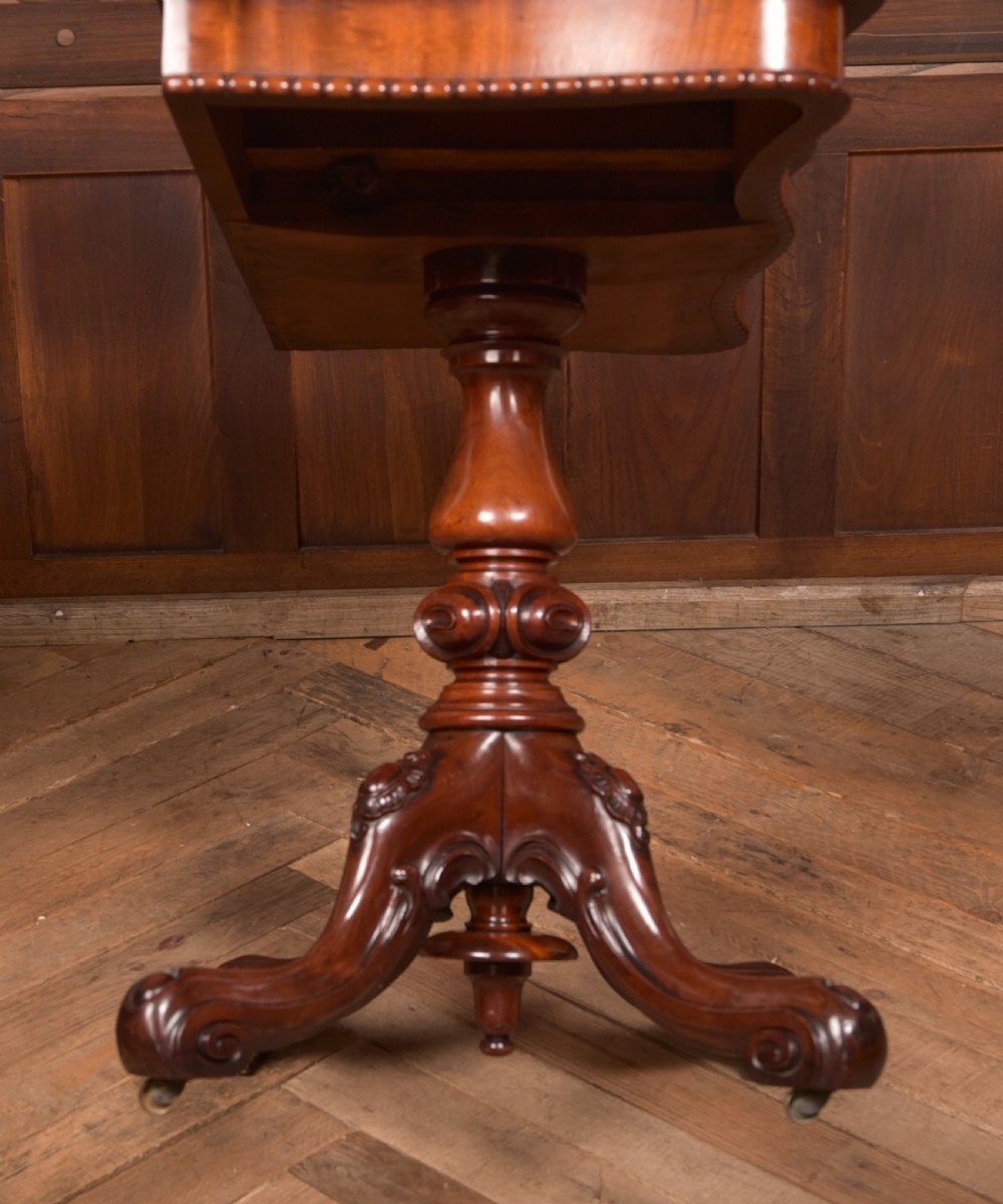 A Victorian mahogany fold-over tea table featuring a serpentine top, bead moulding along the apron, a turned central column, and carved quadruped scroll legs. View XXV