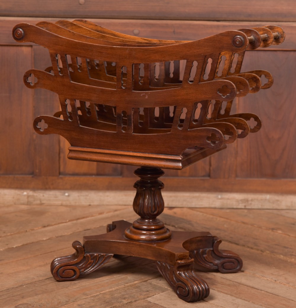 Victorian mahogany sheet music rack featuring pierced fretwork sides, divided compartments, a turned pedestal column, and carved scroll feet.