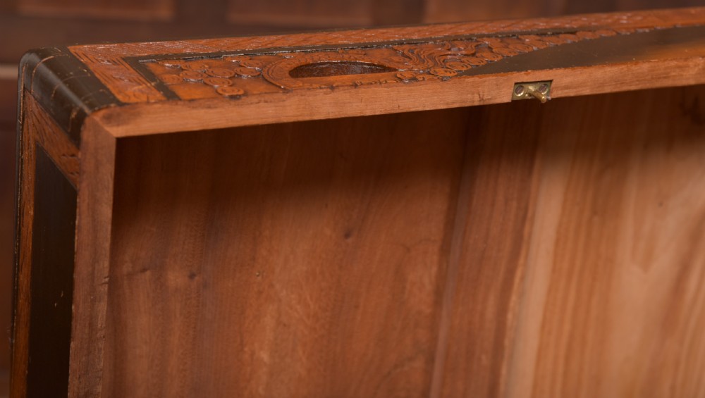 A hand-carved Chinese camphor wood storage chest featuring an oval relief medallion, dragon carvings, and a brass latch plate. View X