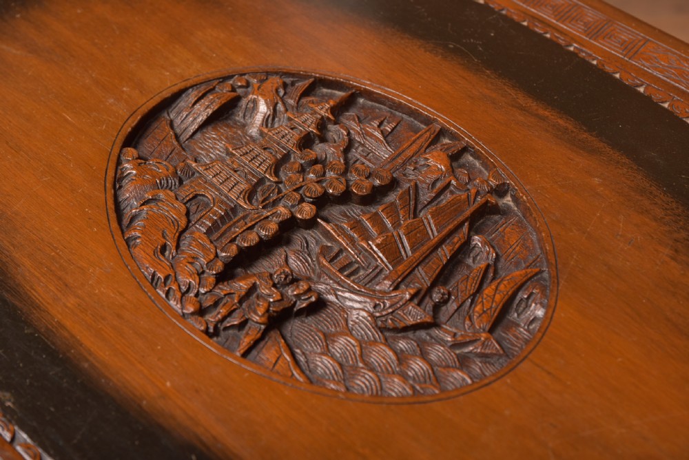 A hand-carved Chinese camphor wood storage chest featuring an oval relief medallion, dragon carvings, and a brass latch plate. View XVIII