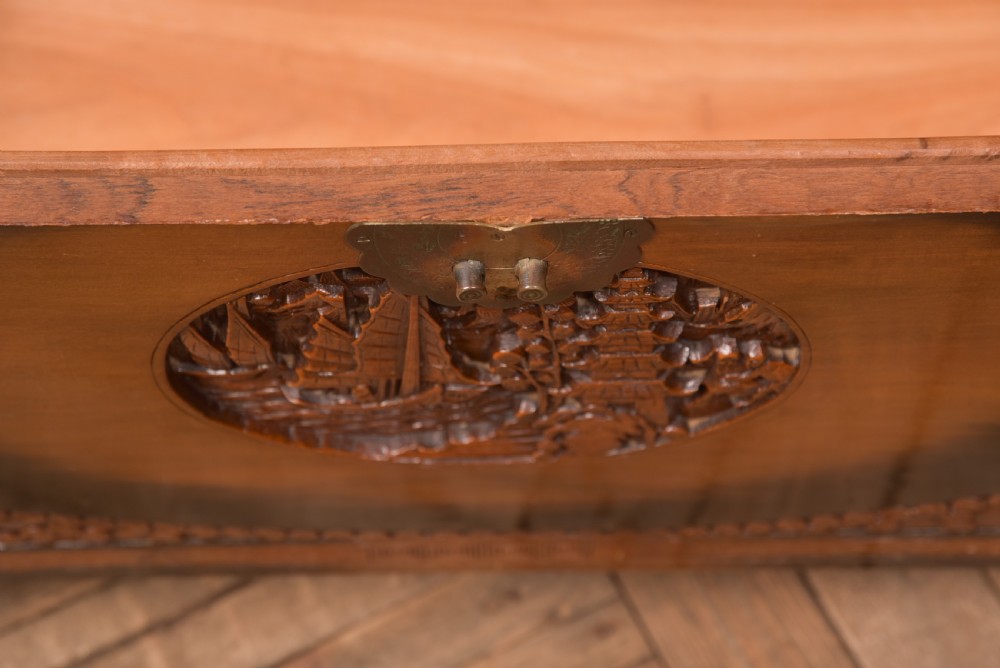A hand-carved Chinese camphor wood storage chest featuring an oval relief medallion, dragon carvings, and a brass latch plate. View XIX