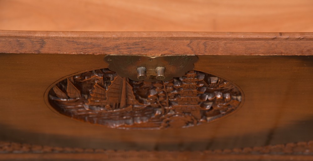 A hand-carved Chinese camphor wood storage chest featuring an oval relief medallion, dragon carvings, and a brass latch plate. View XX