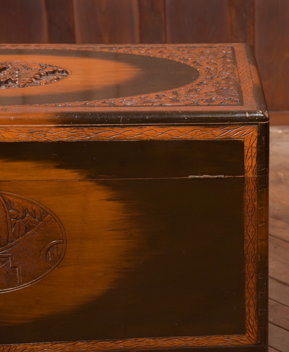 A hand-carved Chinese camphor wood storage chest featuring an oval relief medallion, dragon carvings, and a brass latch plate. View XXIII