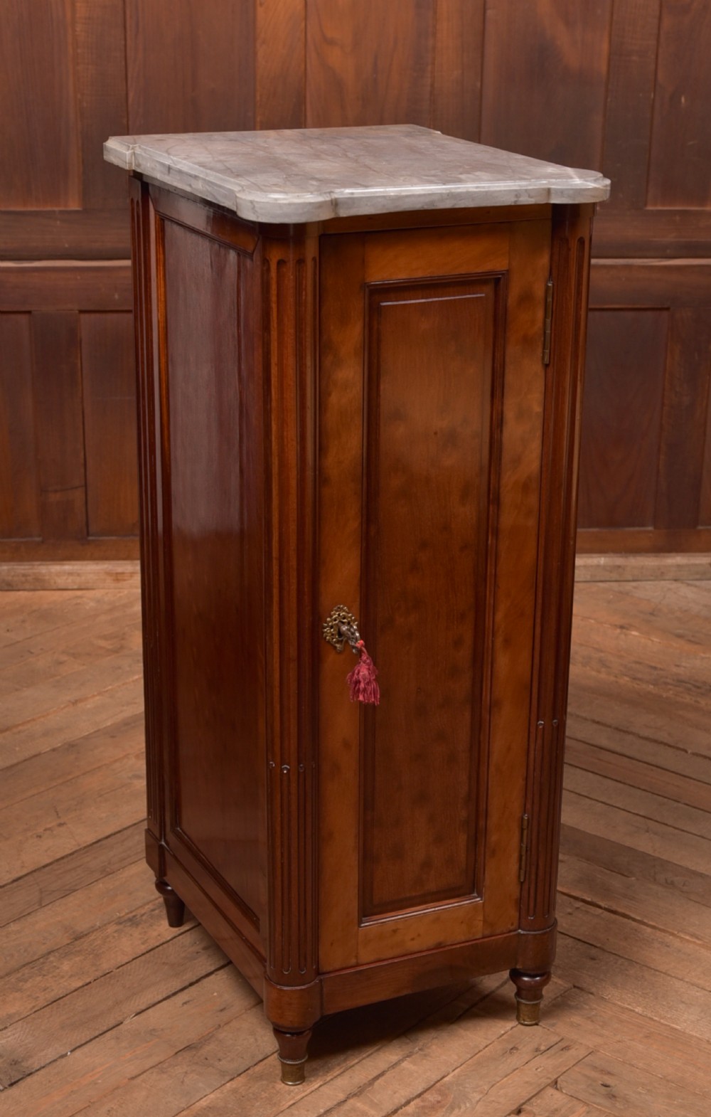A tall Victorian mahogany cabinet featuring a single panelled door, fluted corner columns, a brass escutcheon, and a white marble top.