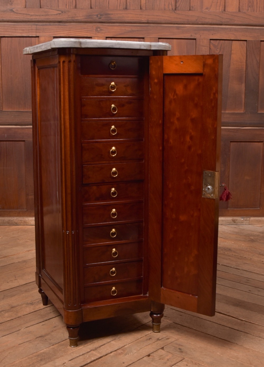 A tall Victorian mahogany cabinet featuring a single panelled door, fluted corner columns, a brass escutcheon, and a white marble top. View VI