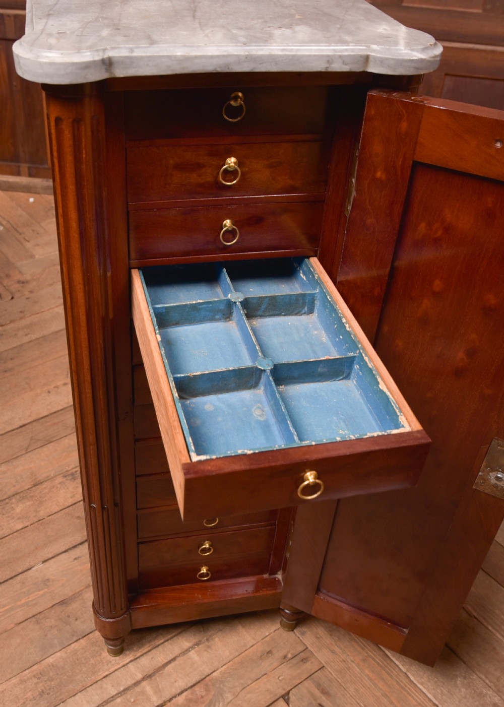A tall Victorian mahogany cabinet featuring a single panelled door, fluted corner columns, a brass escutcheon, and a white marble top. View IX