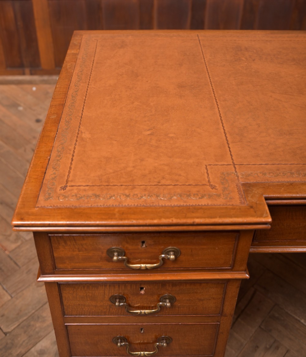 An Edwardian mahogany kneehole writing desk featuring a leather inset top, nine drawers with brass swan neck handles, and carved cabriole legs on ball and claw feet. View II