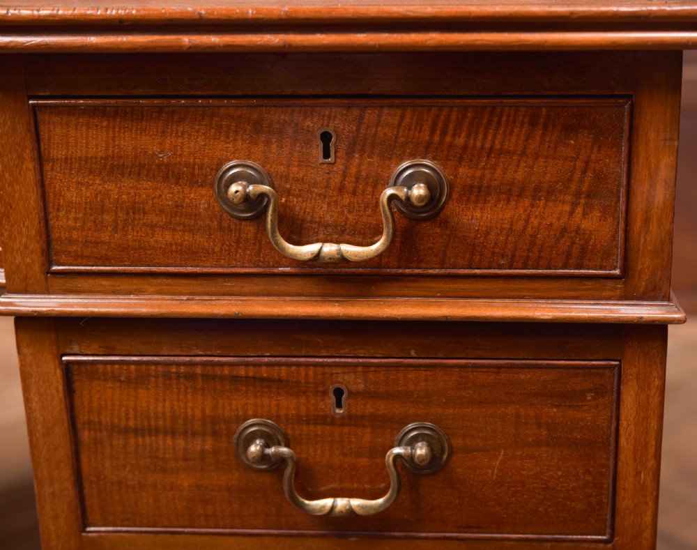 An Edwardian mahogany kneehole writing desk featuring a leather inset top, nine drawers with brass swan neck handles, and carved cabriole legs on ball and claw feet. View V