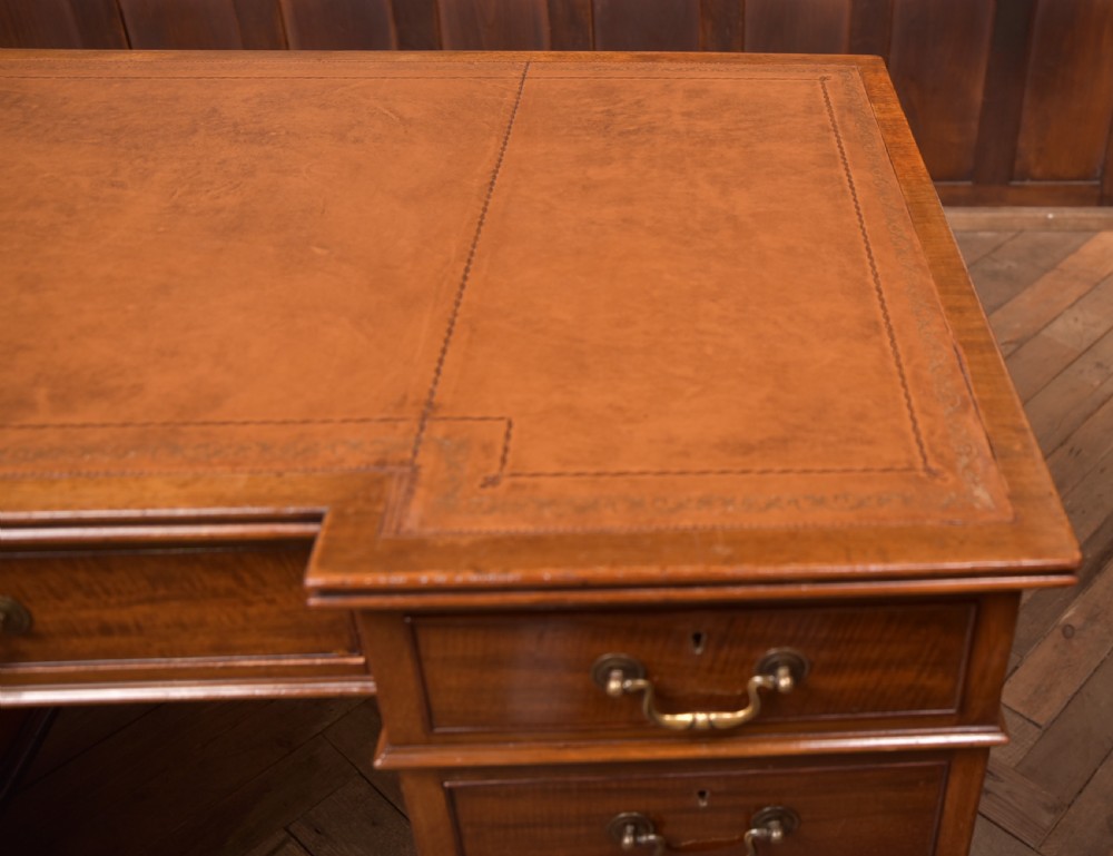 An Edwardian mahogany kneehole writing desk featuring a leather inset top, nine drawers with brass swan neck handles, and carved cabriole legs on ball and claw feet. View VII