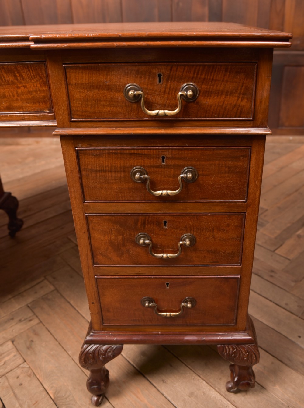 An Edwardian mahogany kneehole writing desk featuring a leather inset top, nine drawers with brass swan neck handles, and carved cabriole legs on ball and claw feet. View VIII
