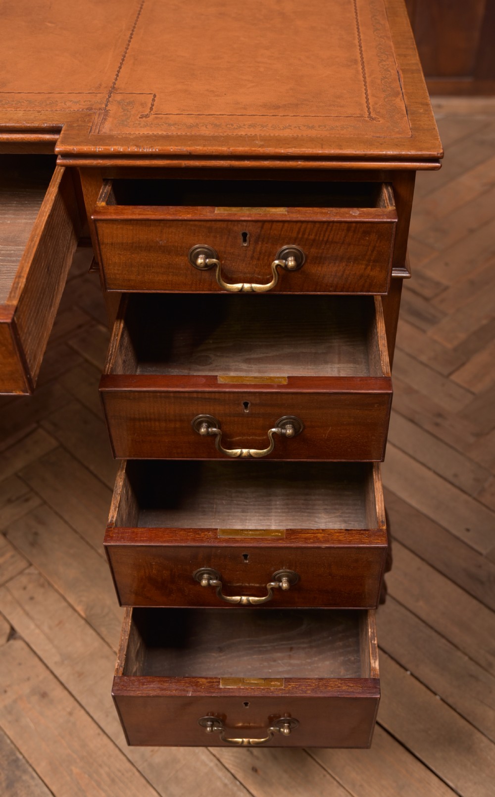 An Edwardian mahogany kneehole writing desk featuring a leather inset top, nine drawers with brass swan neck handles, and carved cabriole legs on ball and claw feet. View X