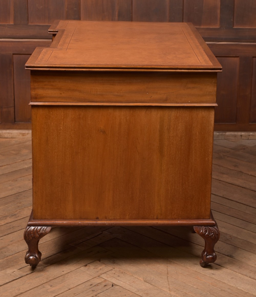 An Edwardian mahogany kneehole writing desk featuring a leather inset top, nine drawers with brass swan neck handles, and carved cabriole legs on ball and claw feet. View XI