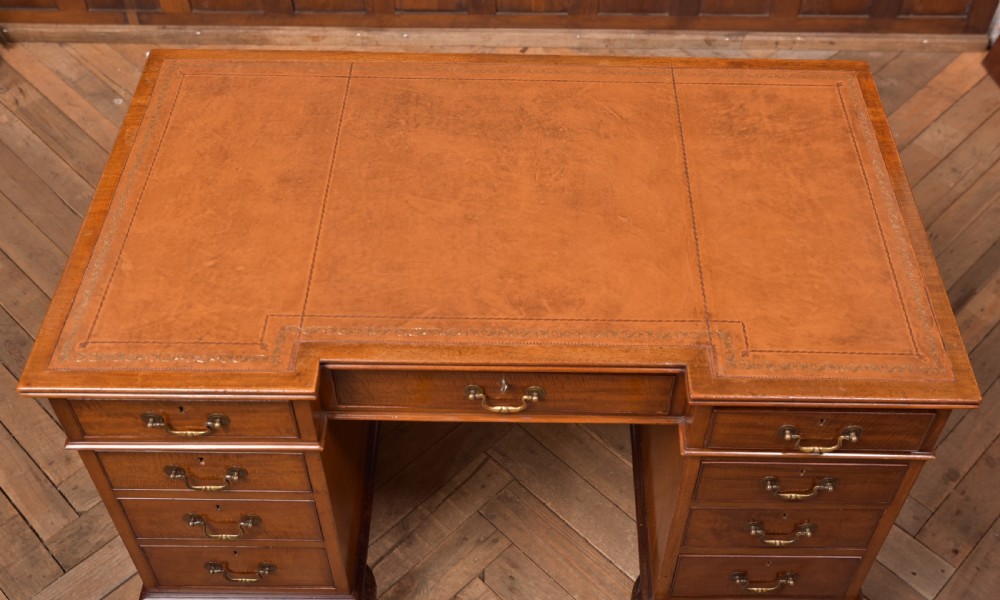 An Edwardian mahogany kneehole writing desk featuring a leather inset top, nine drawers with brass swan neck handles, and carved cabriole legs on ball and claw feet. View XII