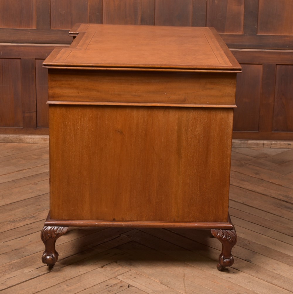 An Edwardian mahogany kneehole writing desk featuring a leather inset top, nine drawers with brass swan neck handles, and carved cabriole legs on ball and claw feet. View XVI