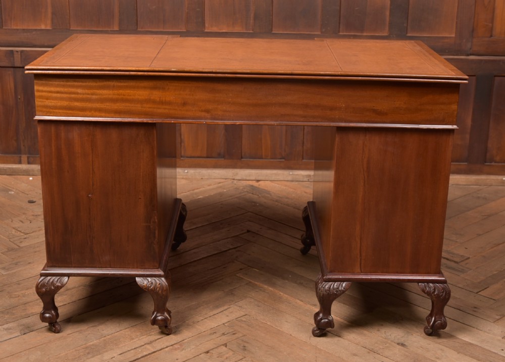 An Edwardian mahogany kneehole writing desk featuring a leather inset top, nine drawers with brass swan neck handles, and carved cabriole legs on ball and claw feet. View XVIII