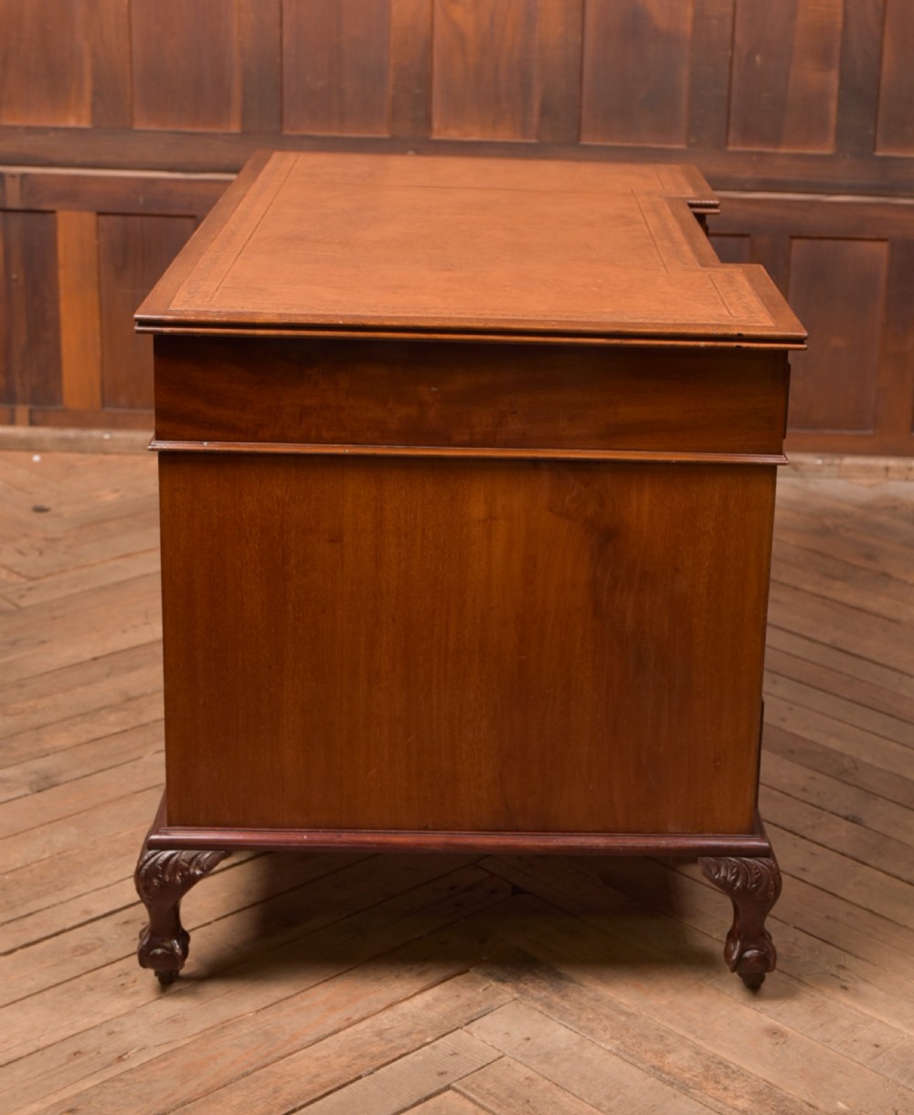 An Edwardian mahogany kneehole writing desk featuring a leather inset top, nine drawers with brass swan neck handles, and carved cabriole legs on ball and claw feet. View XIX