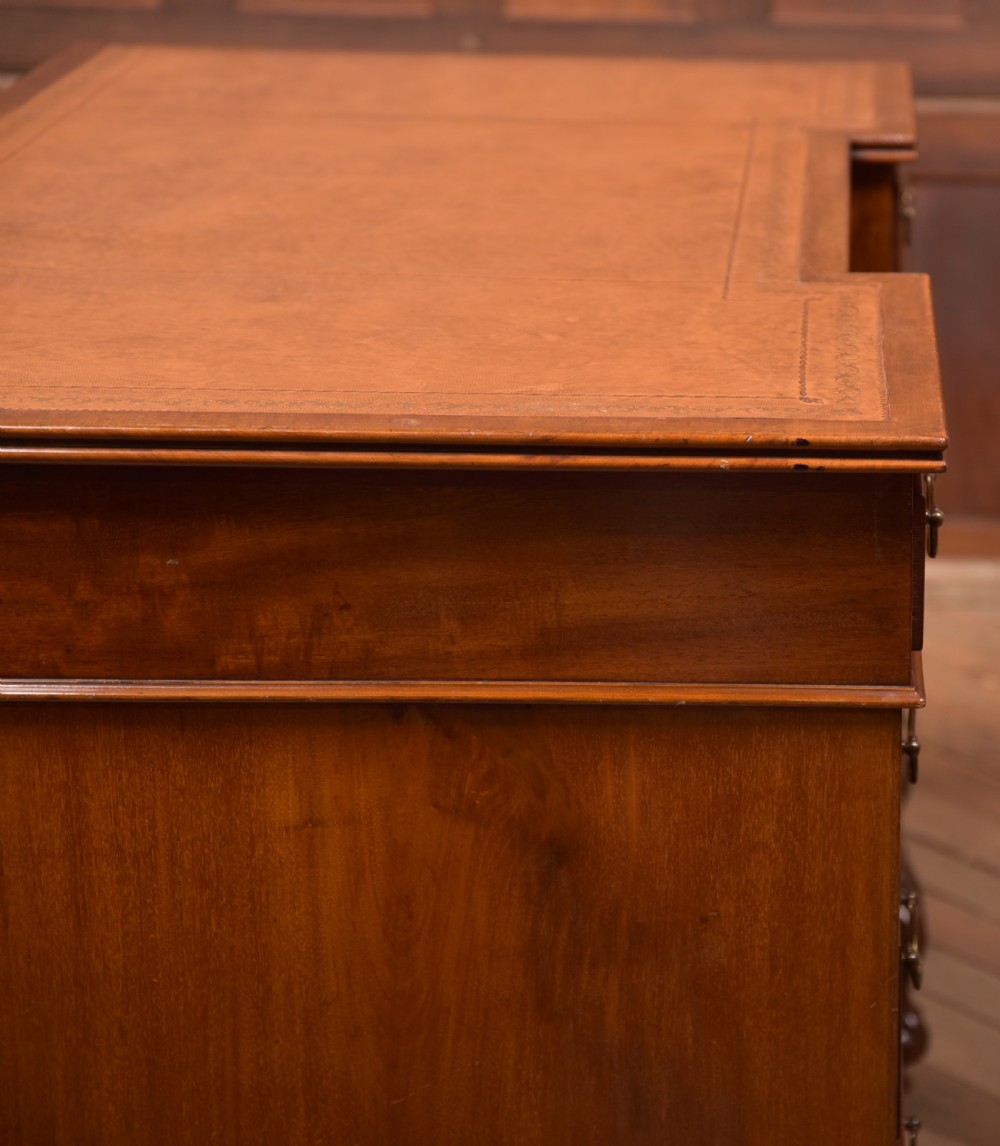 An Edwardian mahogany kneehole writing desk featuring a leather inset top, nine drawers with brass swan neck handles, and carved cabriole legs on ball and claw feet. View XX