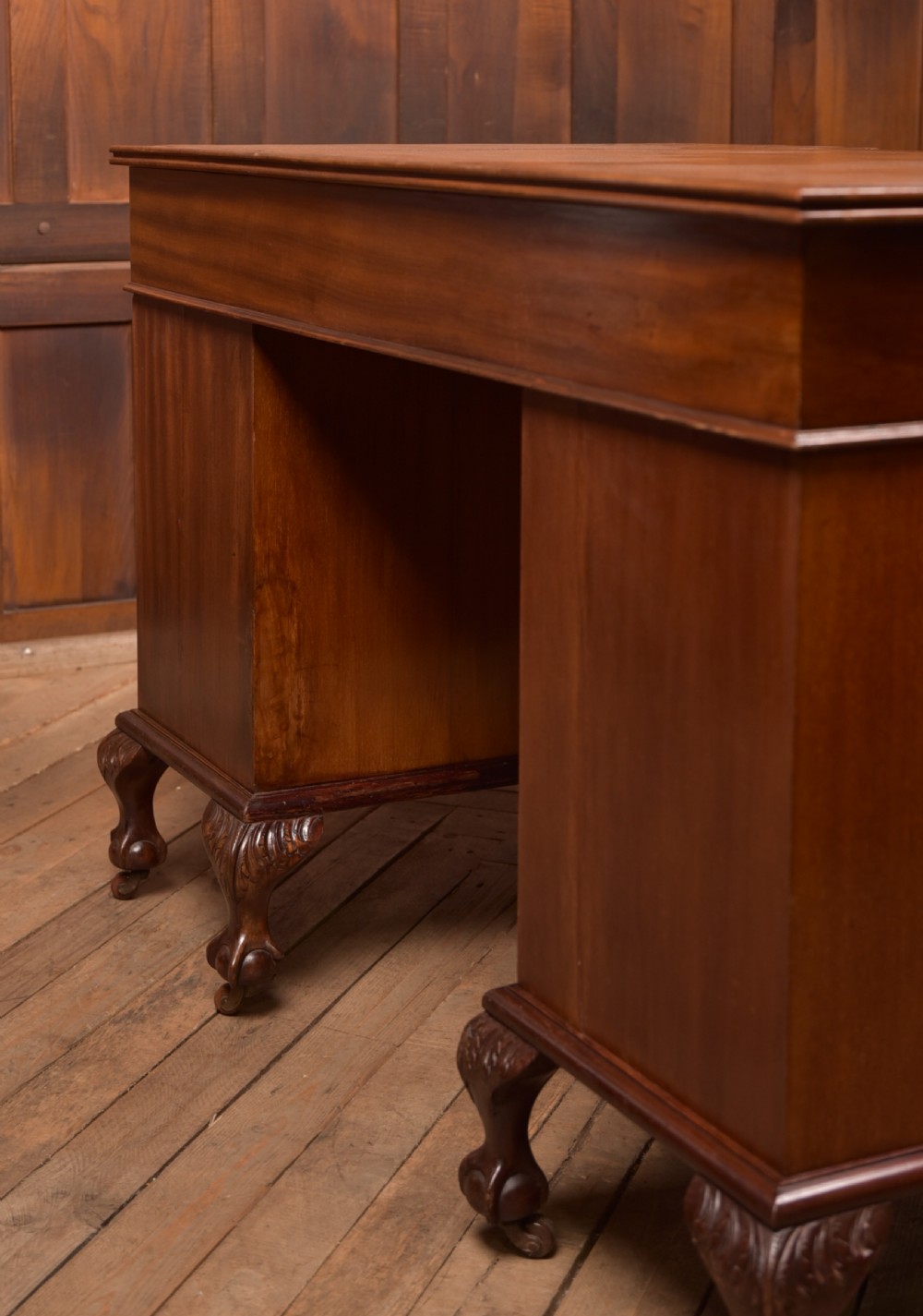 An Edwardian mahogany kneehole writing desk featuring a leather inset top, nine drawers with brass swan neck handles, and carved cabriole legs on ball and claw feet. View XXV
