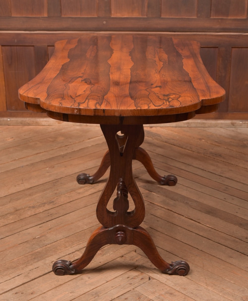 A Victorian rosewood stretcher table featuring a figured top with lobed ends, pierced trestle supports, a barley twist stretcher, and scrolled feet. View VIII