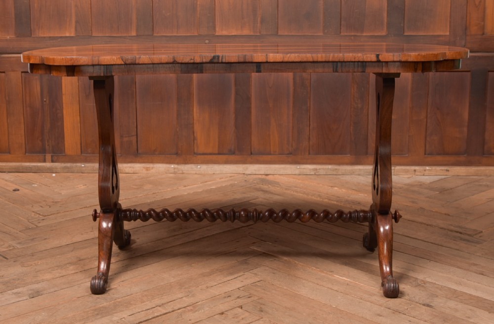 A Victorian rosewood stretcher table featuring a figured top with lobed ends, pierced trestle supports, a barley twist stretcher, and scrolled feet. View IX