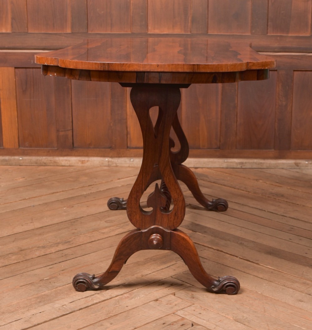 A Victorian rosewood stretcher table featuring a figured top with lobed ends, pierced trestle supports, a barley twist stretcher, and scrolled feet. View X