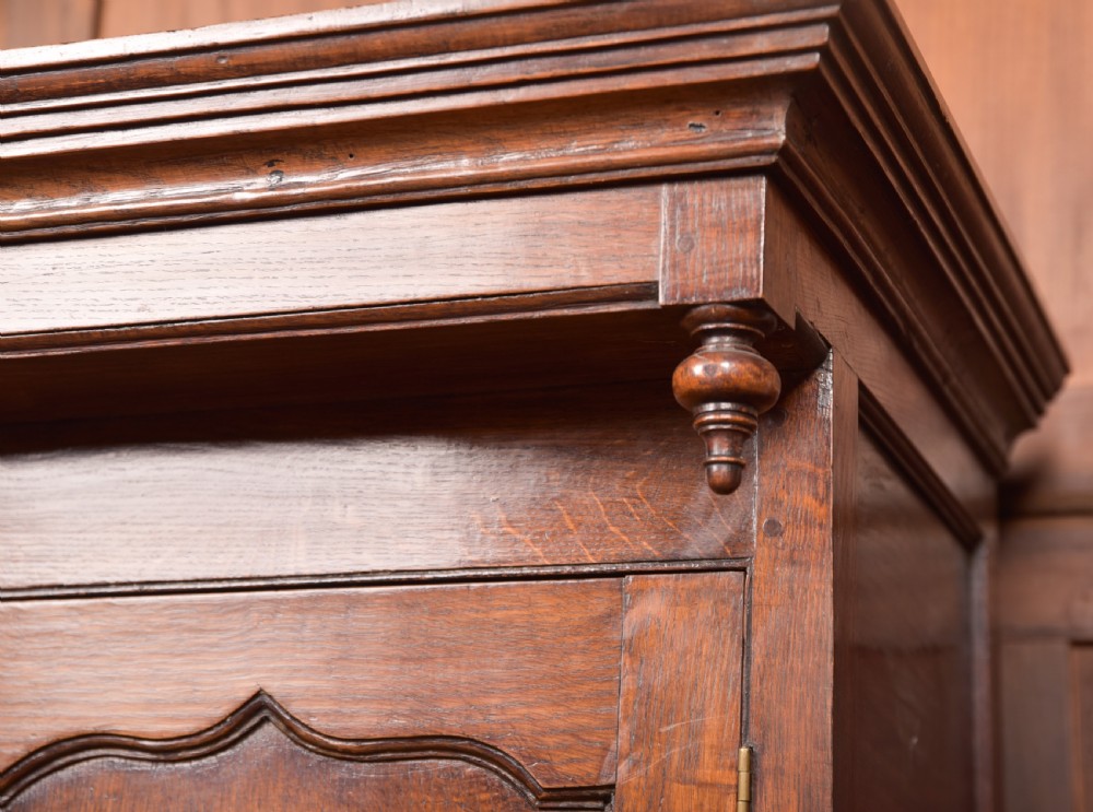A two-tiered nineteenth-century oak court cupboard featuring panelled doors, drop handles on two upper drawers, and turned finials. View V